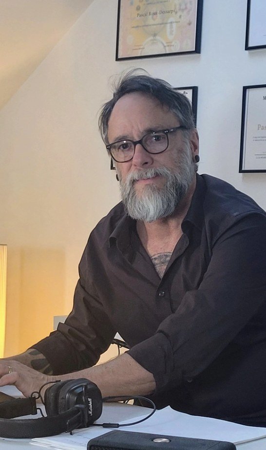 Pascal Roux-Dessarps, maître enseignant Reiki, dans son bureau devant ses certifications